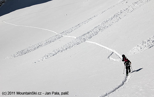 Snowboardistka na sněžnicích šlape skialpovou stopou