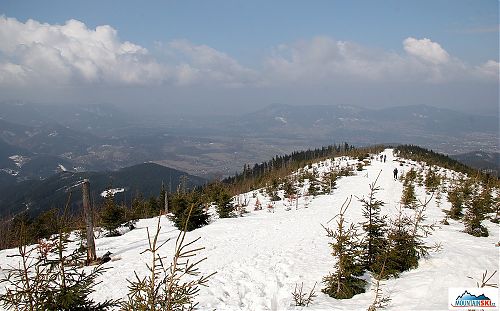 V údolích je jaro, na hřebenu spousta sněhu a částečně pod sněhem je i vrcholová část Ondřejníku na pozadí