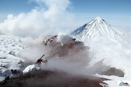 Roman & Matúš climbing through fumarole at the top of volcano Avachinsky, volcano Koryaksky in the background